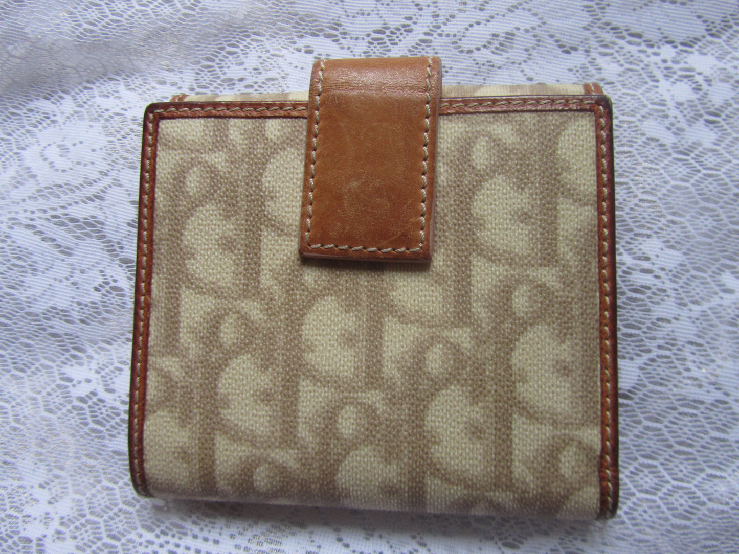 Beige wallet with brown leather accents on a lace background