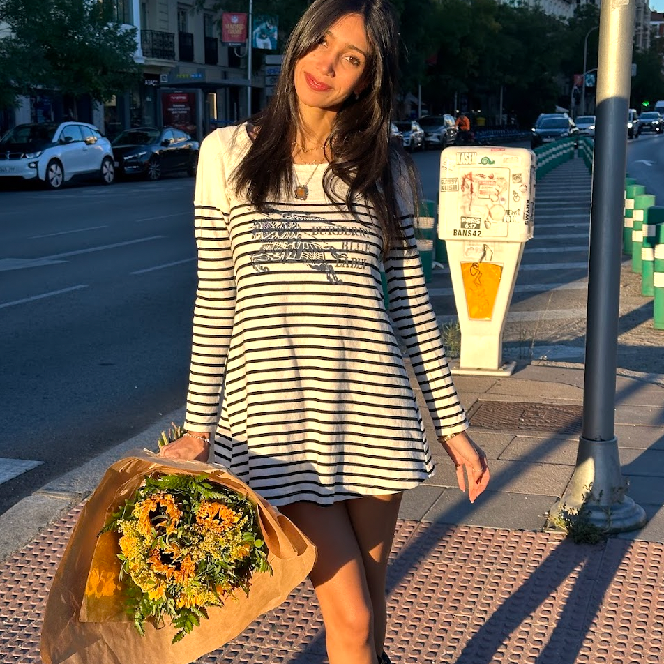 Woman in a striped dress holding flowers on a city street
