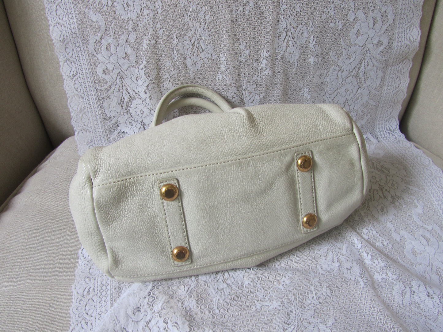 Beige handbag with gold accents on a white lace background