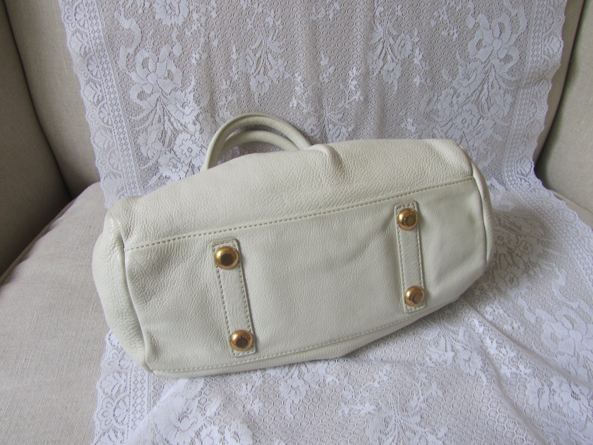 Beige handbag with gold accents on a white lace background
