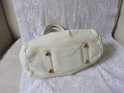 Beige handbag with gold accents on a white lace background
