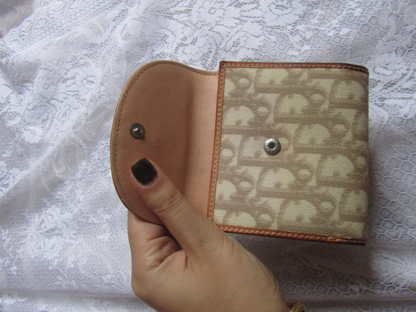Hand holding a patterned wallet against a textured white background