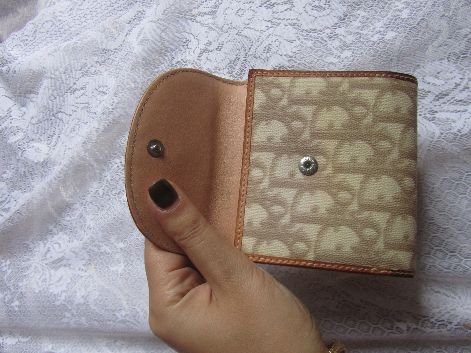Hand holding a patterned wallet against a textured white background