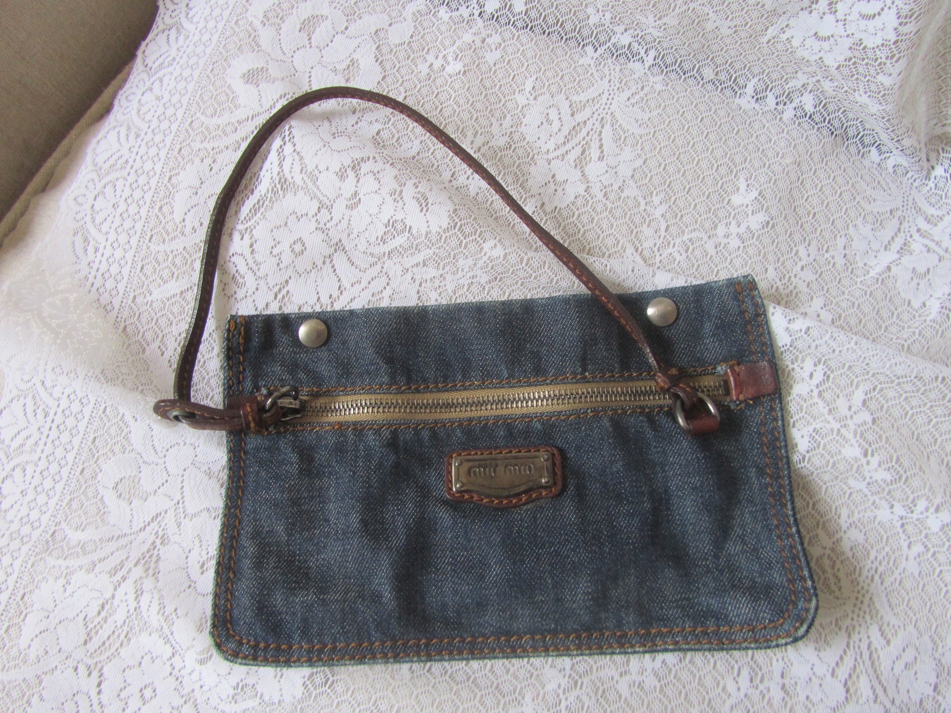 Denim handbag with brown handle on a textured surface
