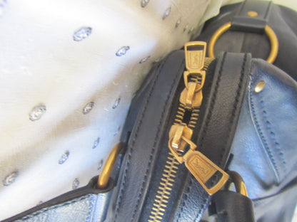 Close-up of a gold zipper on a black leather bag with a white interior.