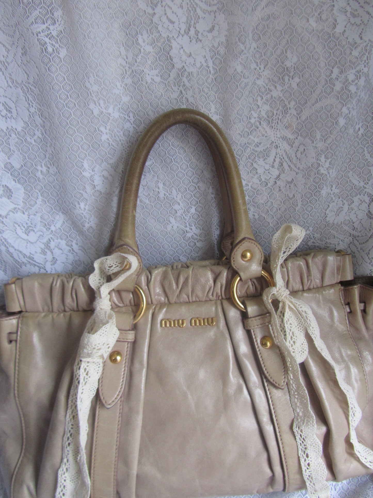 Beige handbag with lace detailing on a textured surface