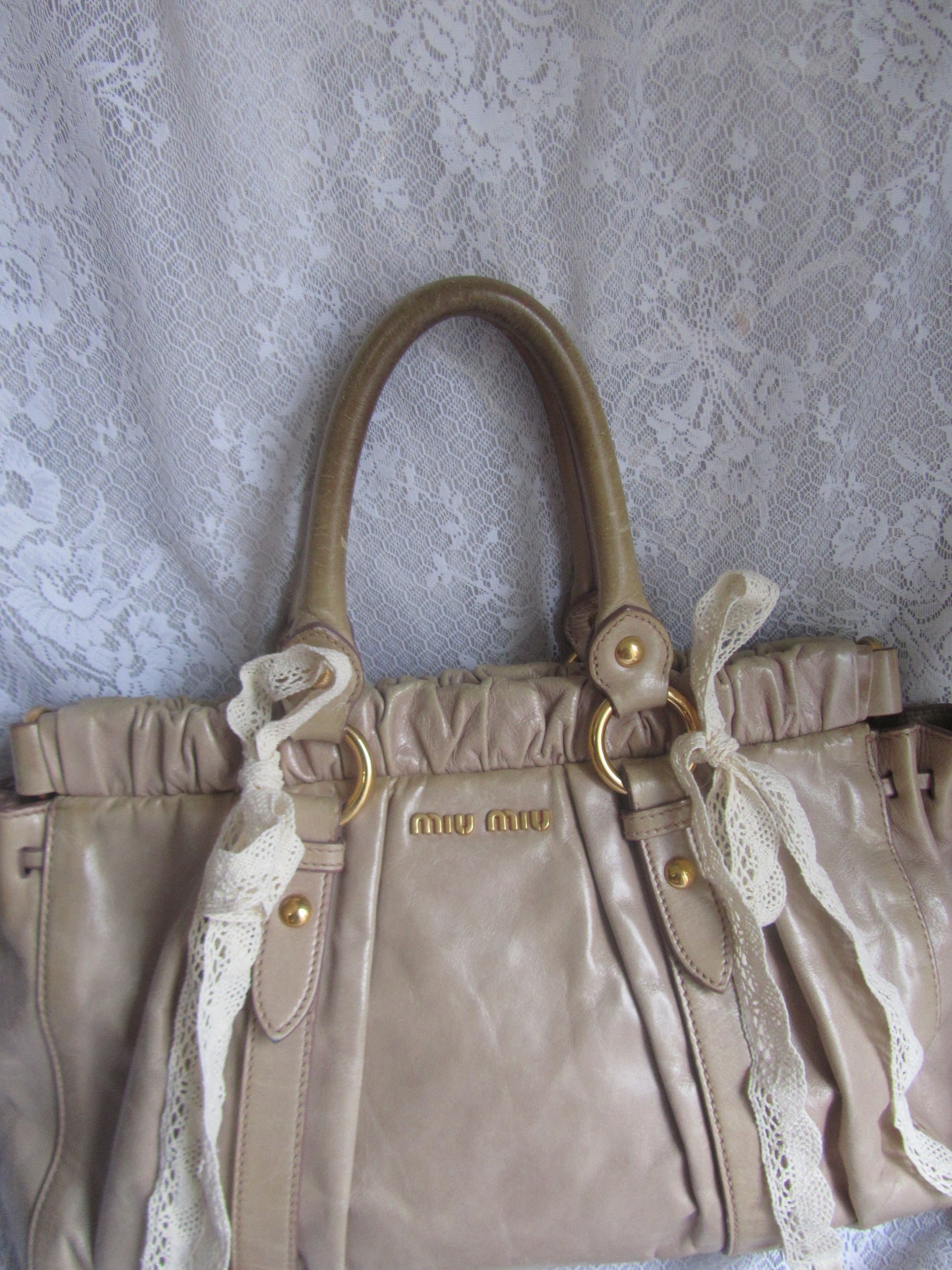Beige handbag with lace detailing on a textured surface