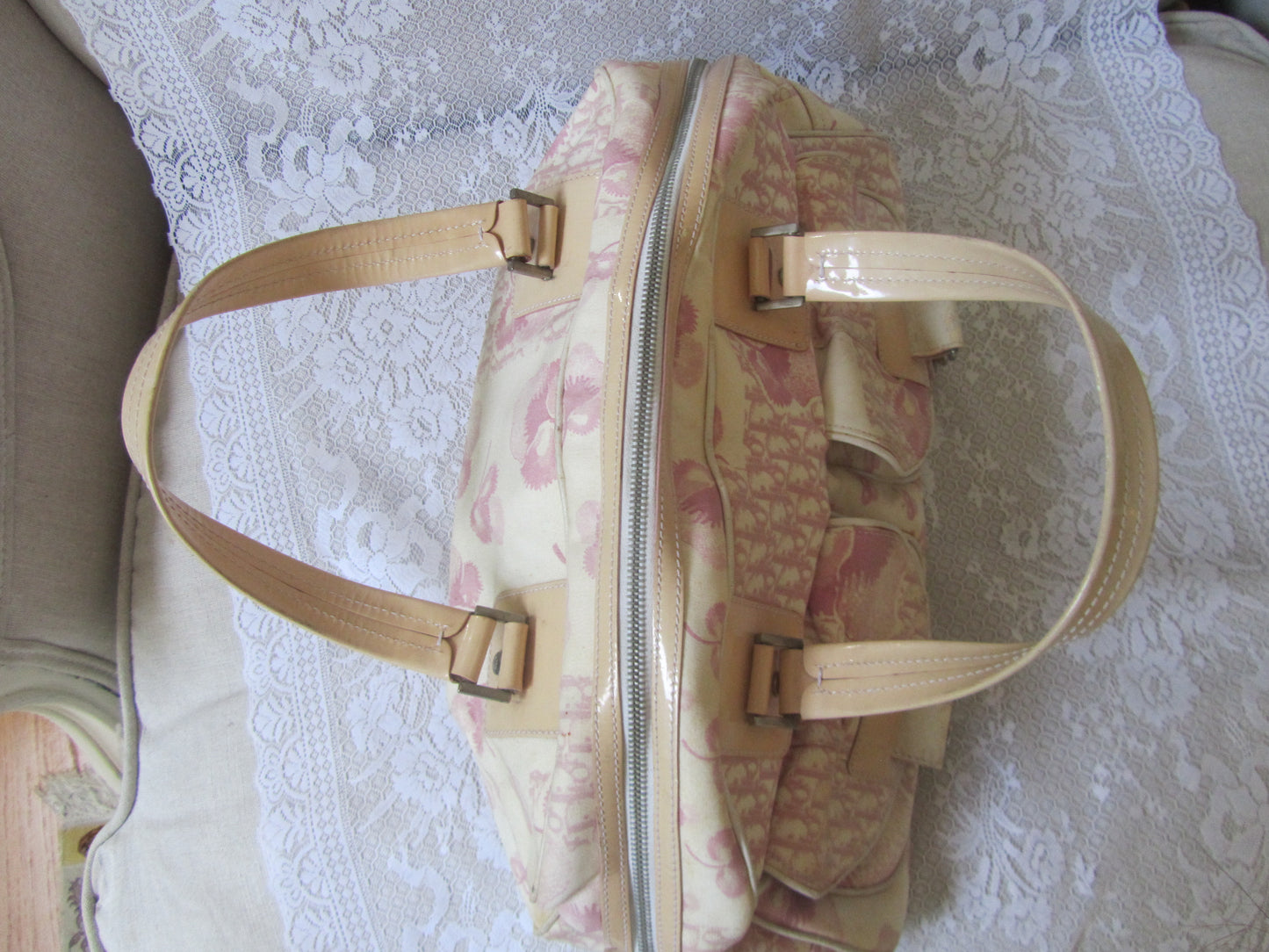 Floral-patterned handbag with beige straps on a textured surface