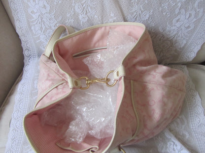 Pink handbag with gold accents on a textured white surface