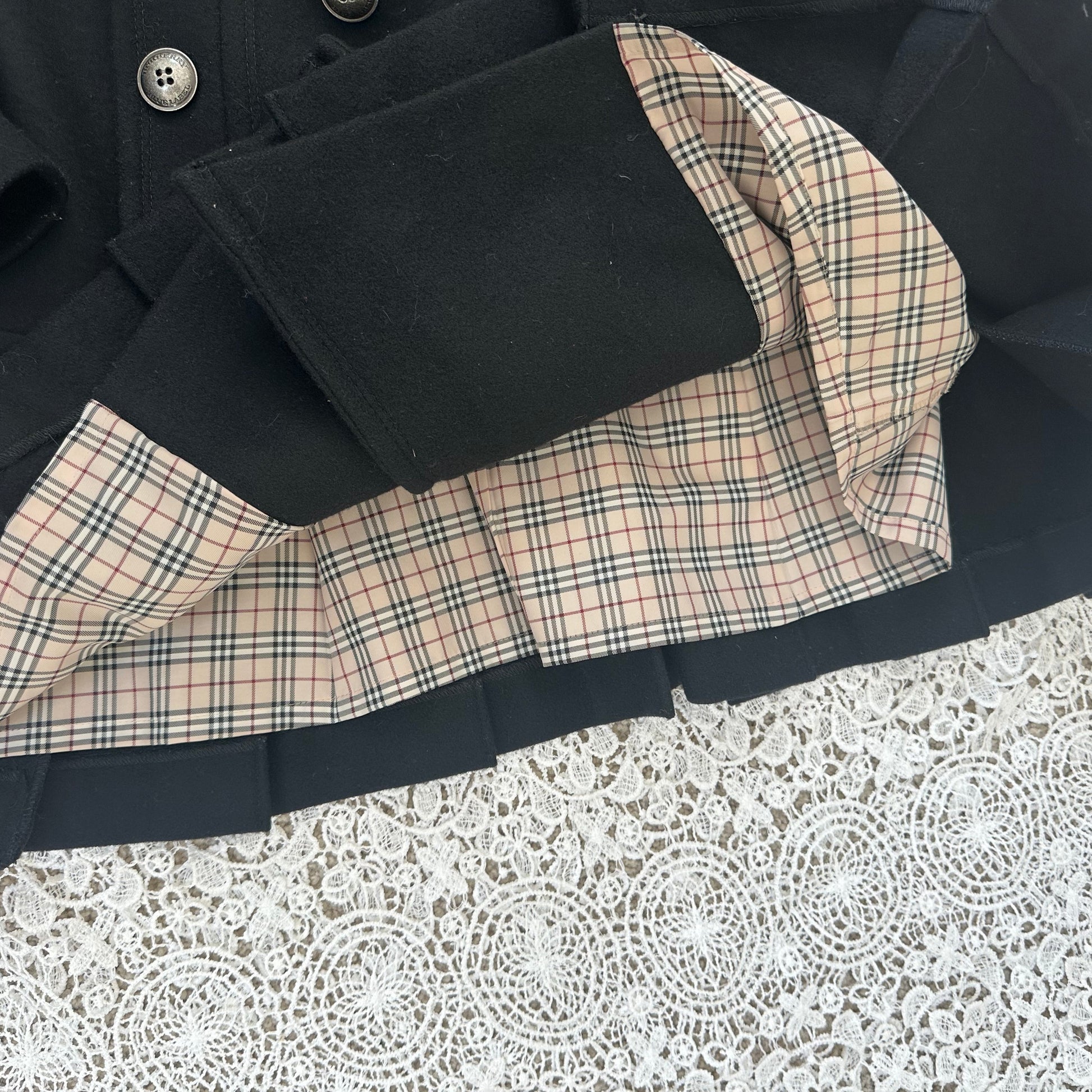 Black coat with plaid lining on a textured white background