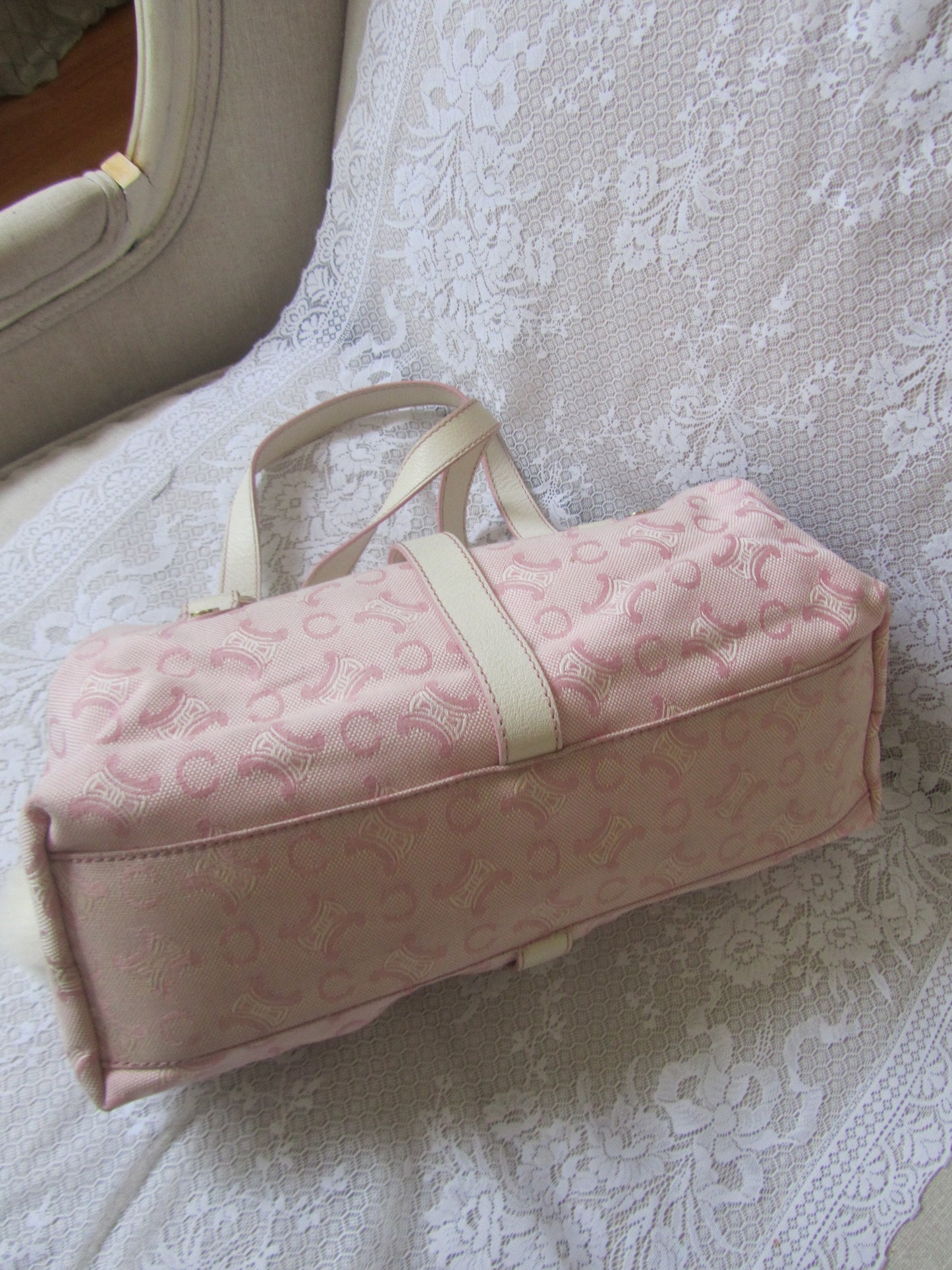 Pink textured bag with a strap on a lace-covered surface