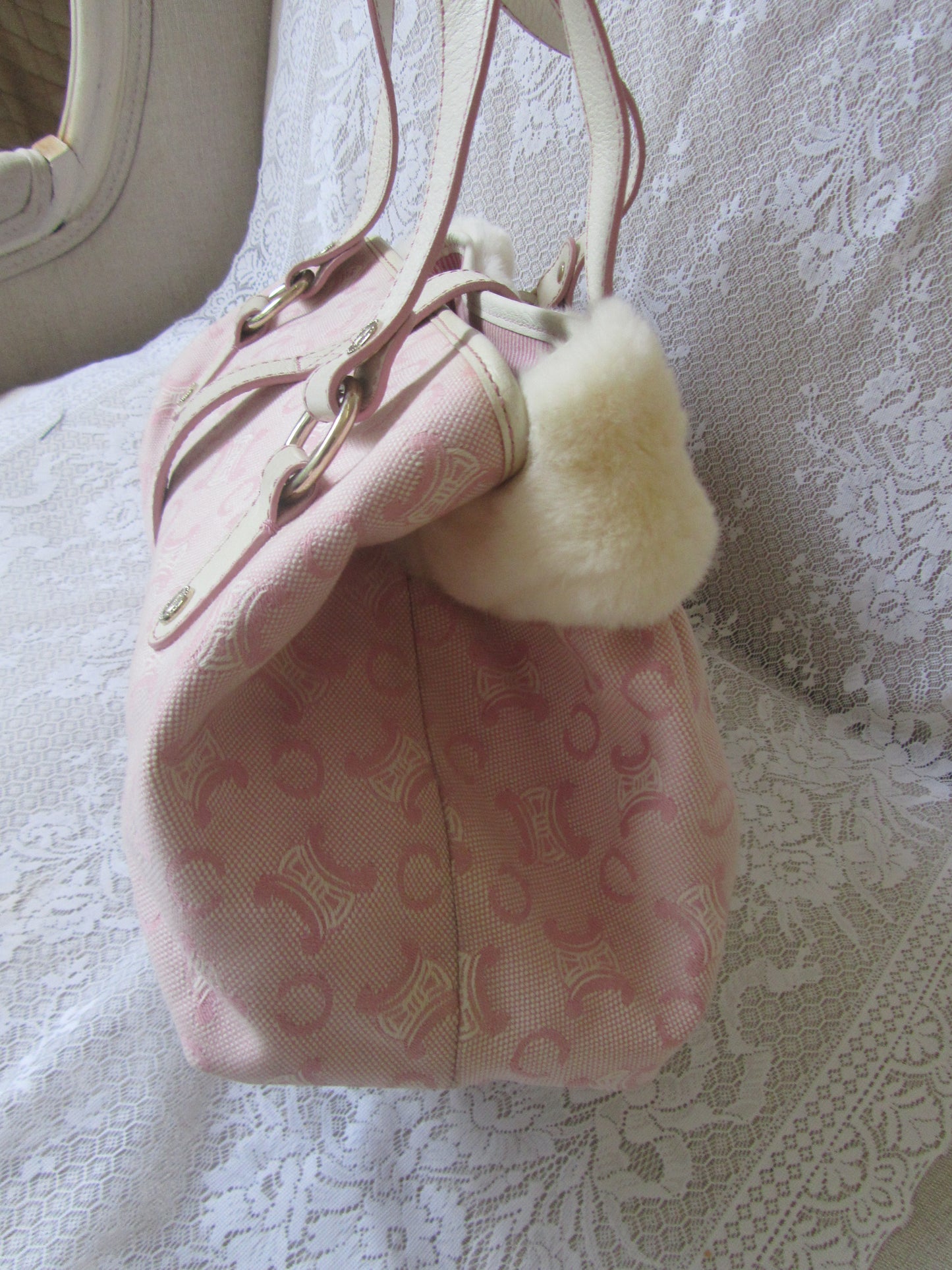 Pink handbag with fur detail on a textured white surface