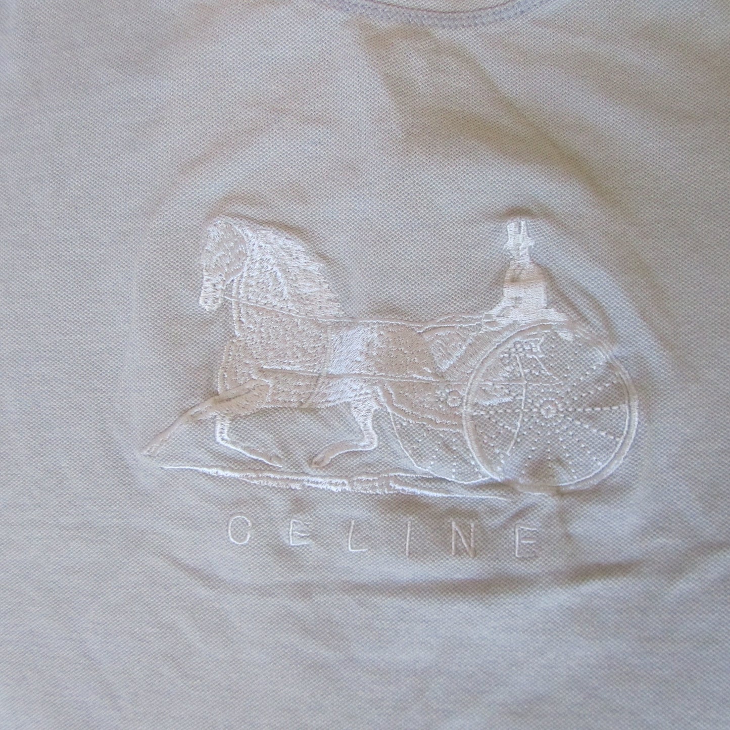 Embroidered rocking horse design on a beige fabric with 'Geline' branding.