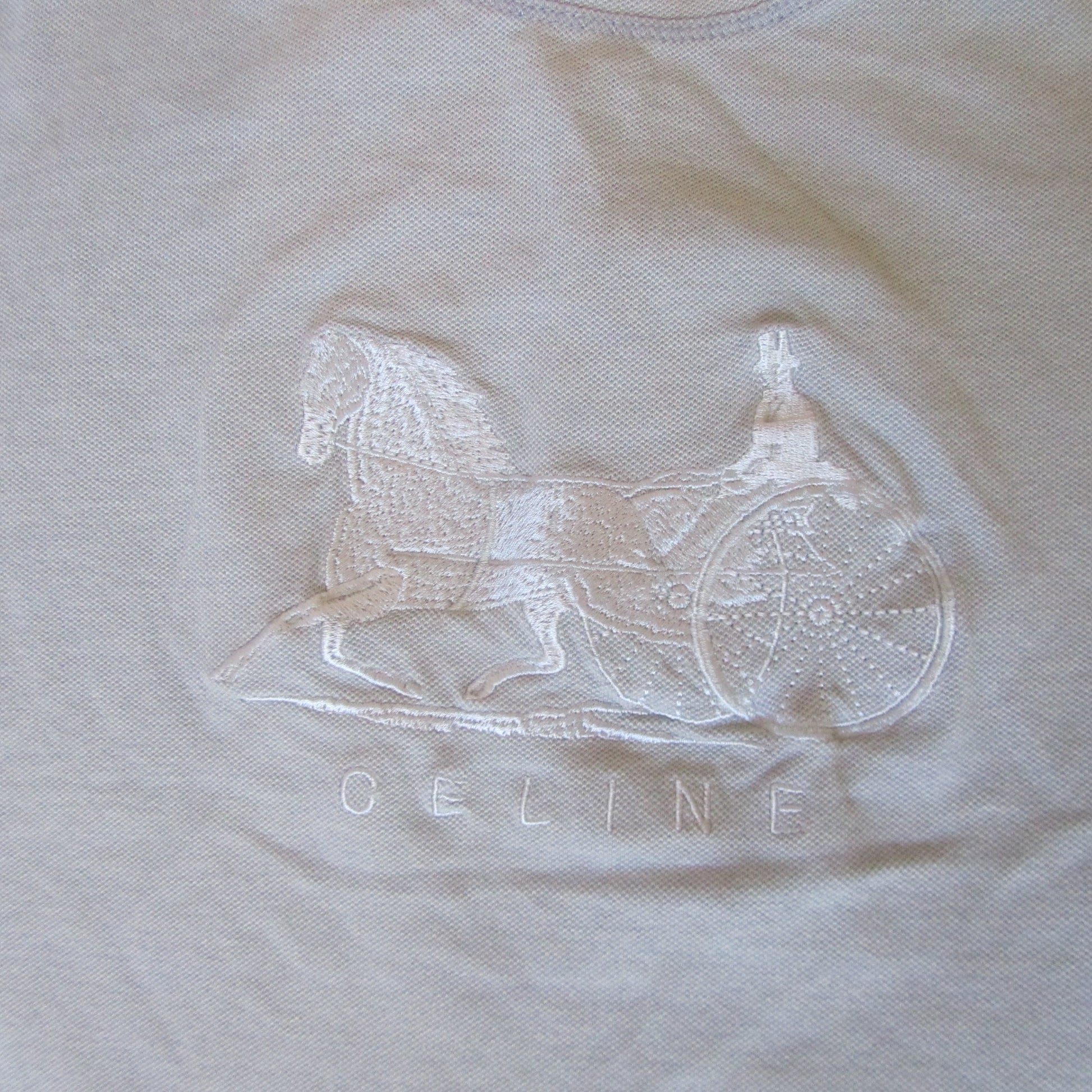 Embroidered rocking horse design on a beige fabric with 'Geline' branding.