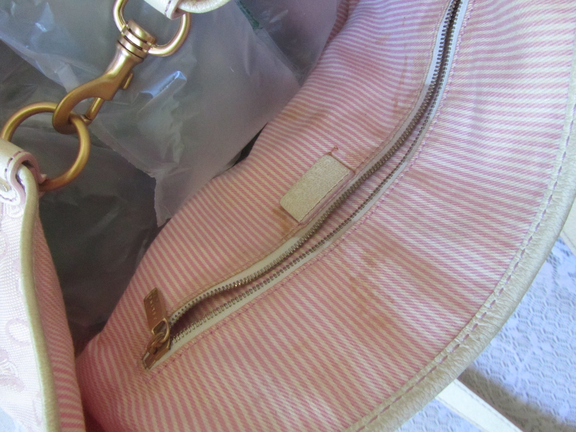 Close-up of a pink textured handbag with gold zipper and hardware.