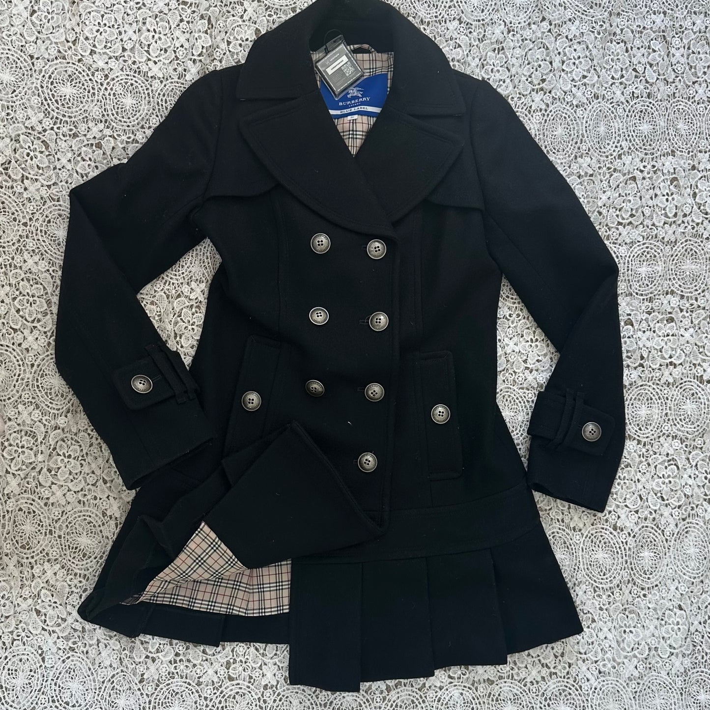 Black peacoat with plaid lining on a textured white background