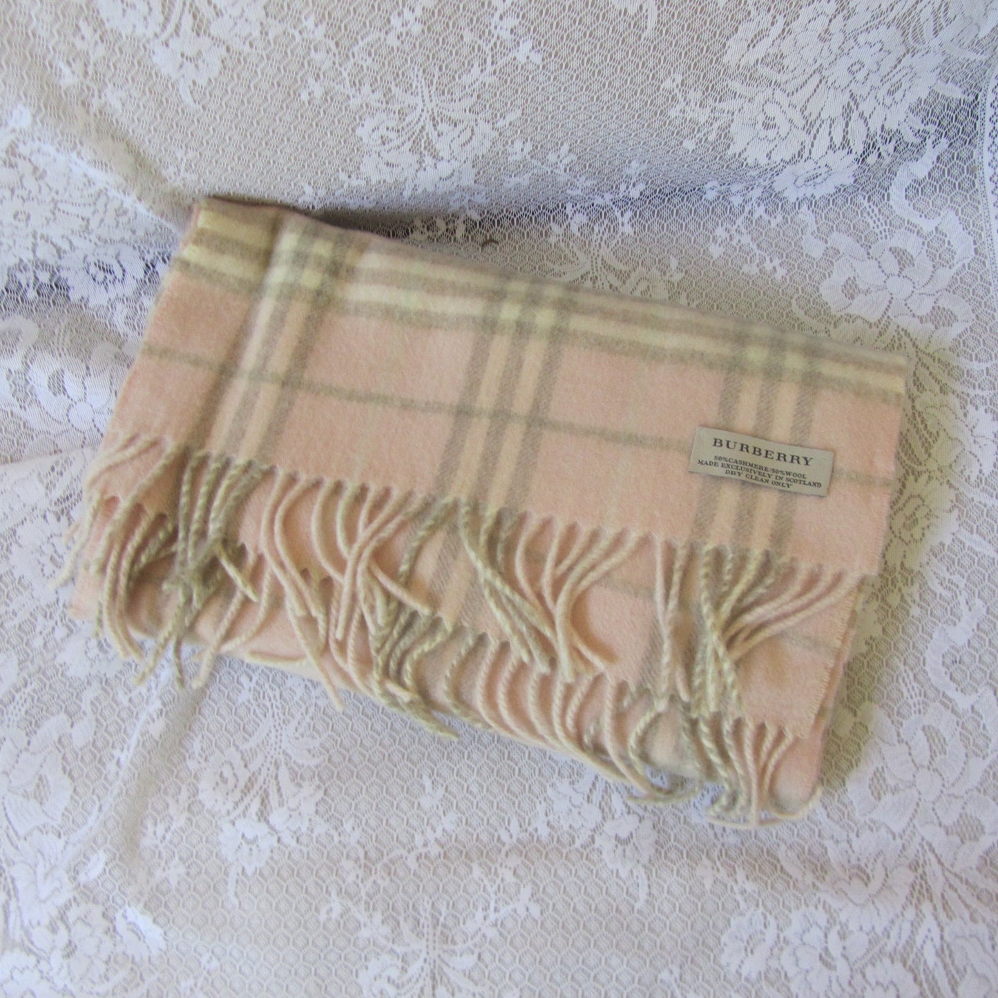 Plaid scarf with a brand label on a textured white surface