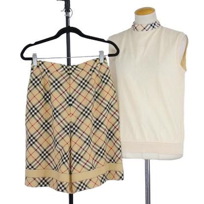 Plaid skirt on a hanger and cream sleeveless top on a mannequin against a white background