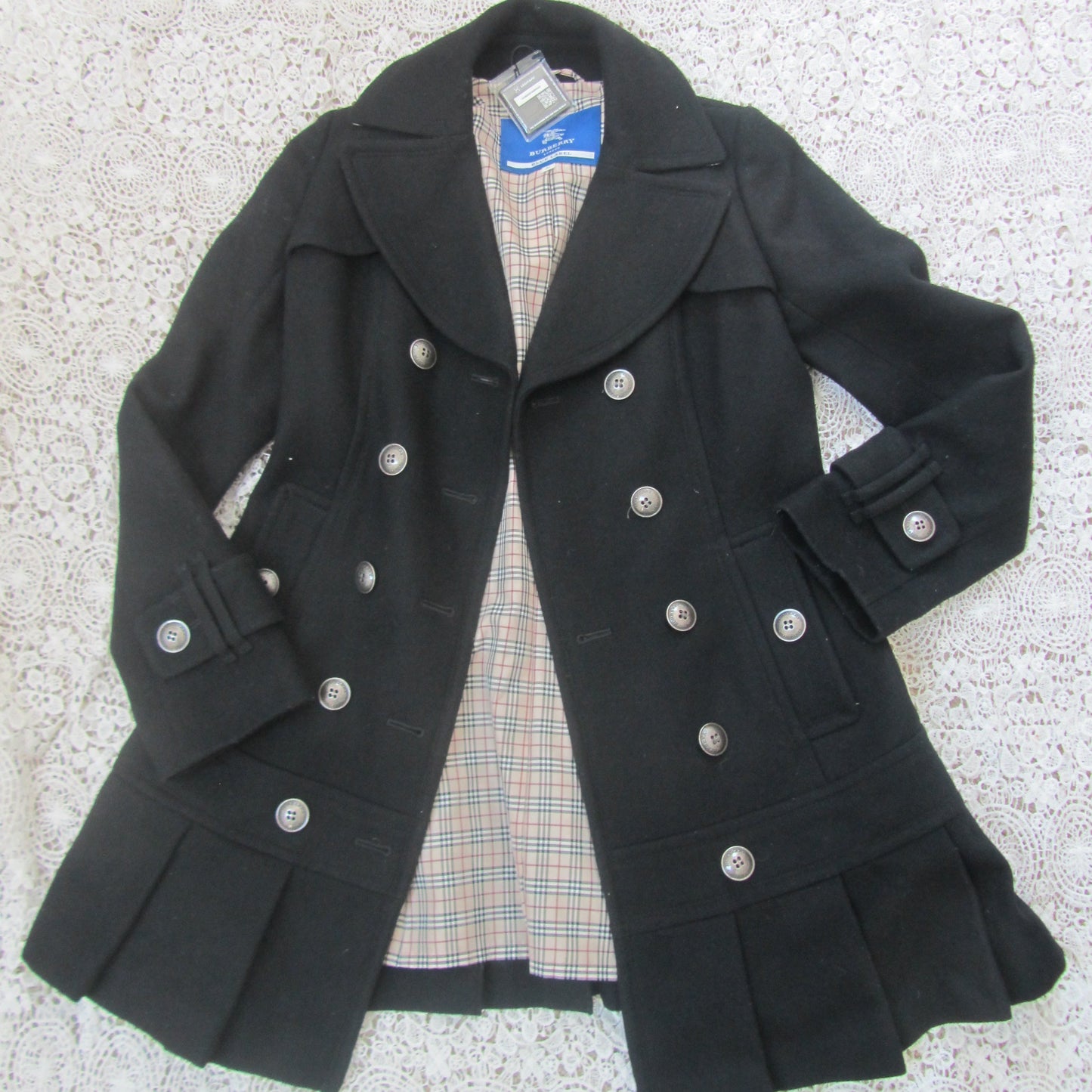 Black coat with silver buttons on a textured surface
