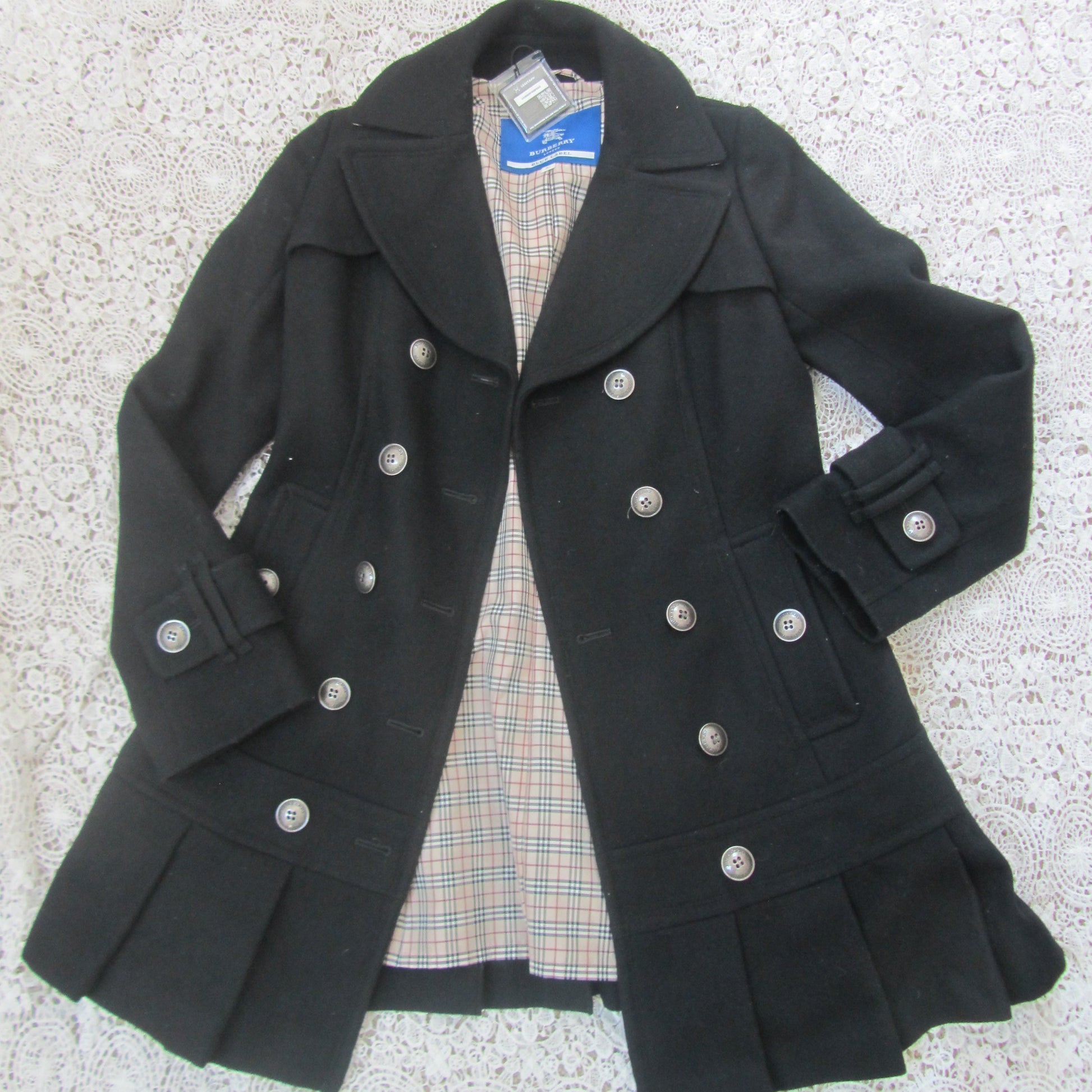 Black coat with silver buttons on a textured surface