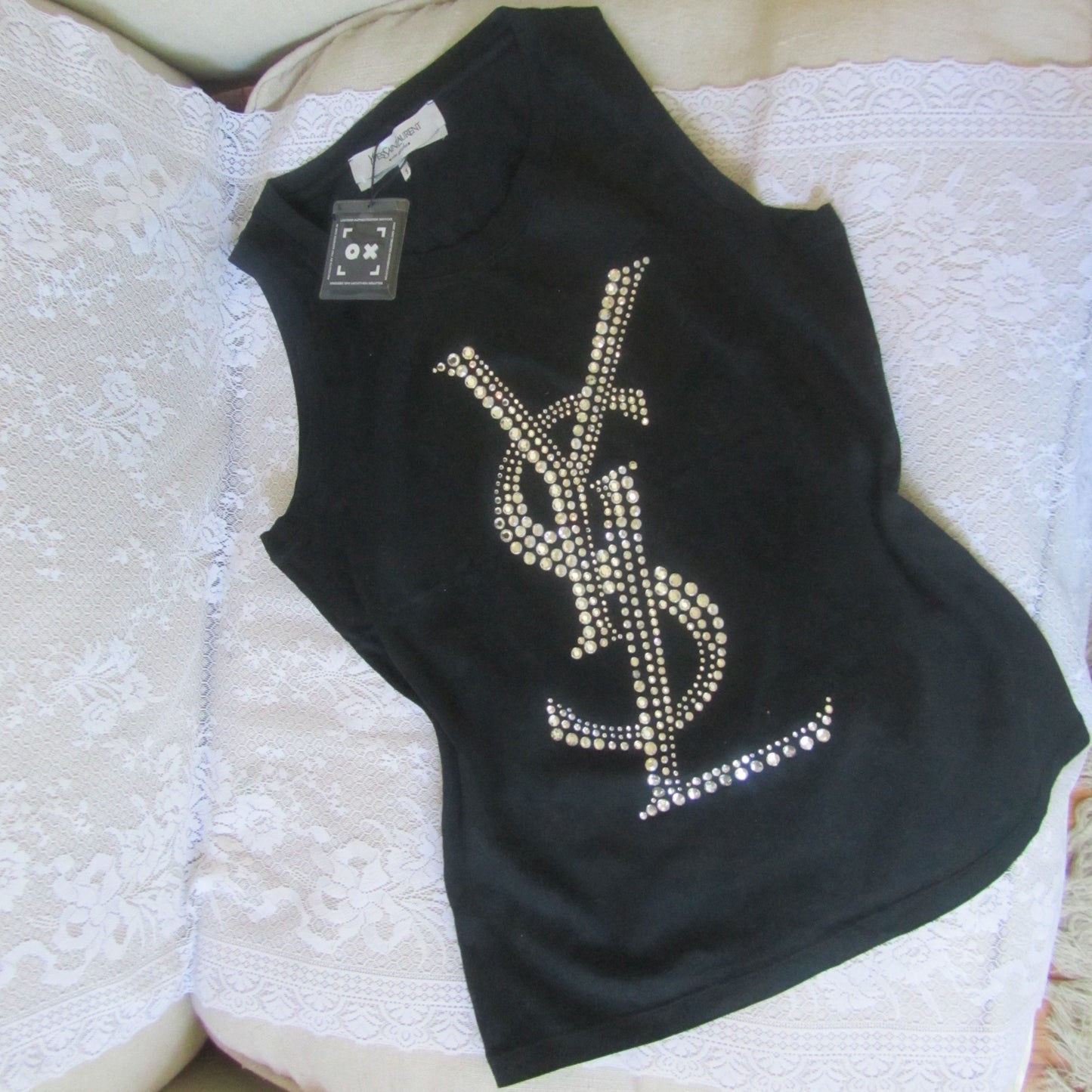 Black t-shirt with rhinestone design on a white textured surface