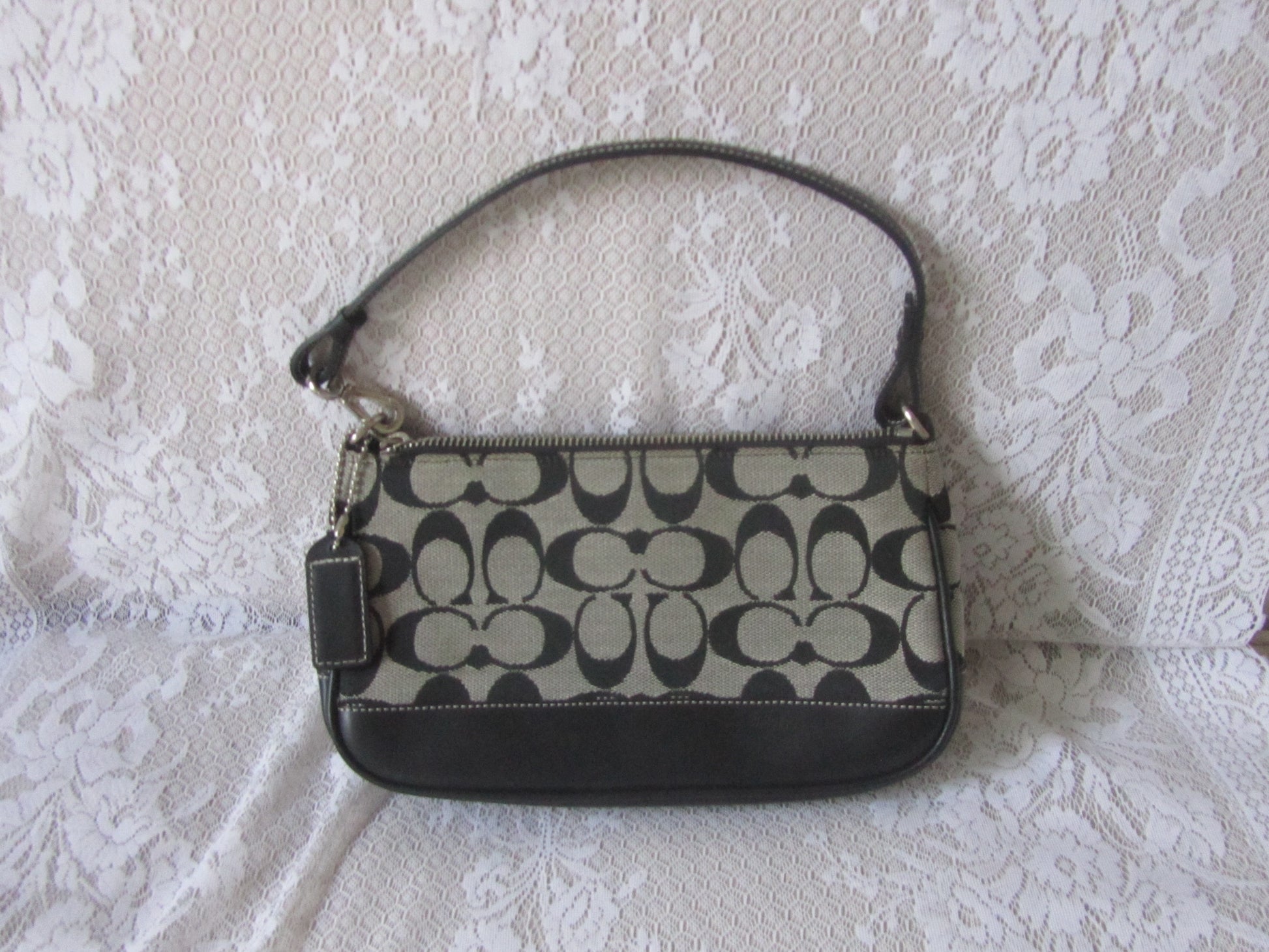 Coach handbag with black and beige pattern on a textured white surface