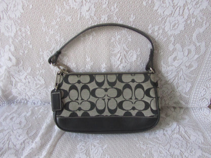 Coach handbag with black and beige pattern on a textured white surface