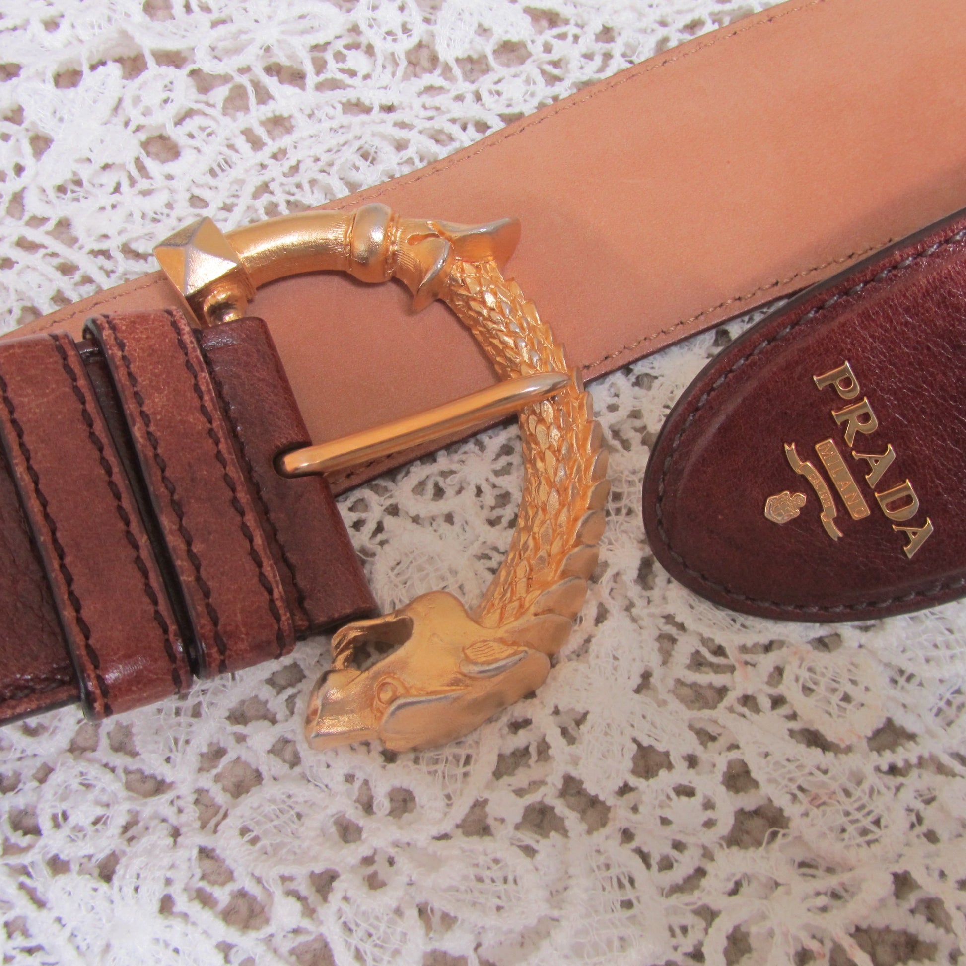 brown prada belt with gold buckle and gold detailing on lace background