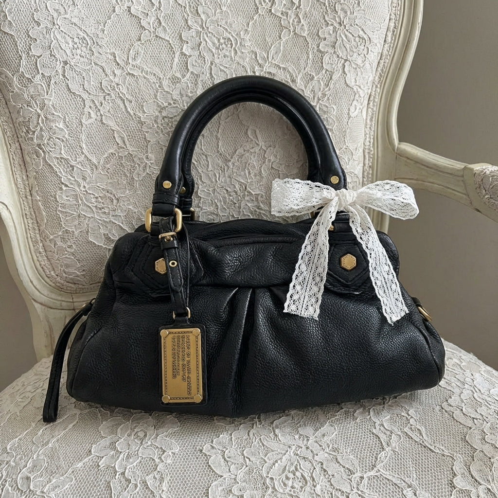 Black handbag with a lace bow on a lace-covered chair
