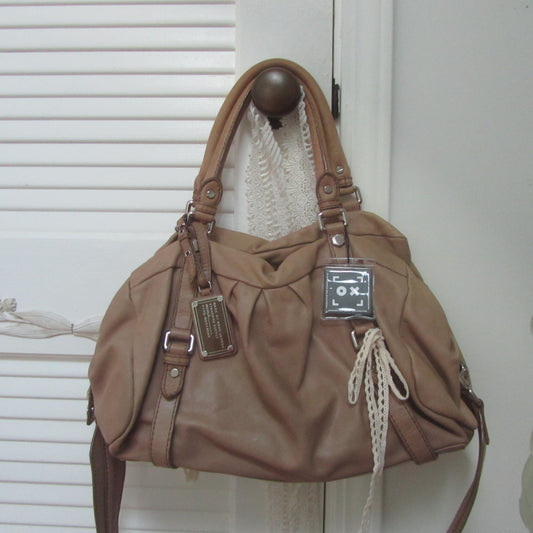 Brown handbag with a visible brand tag on a white background