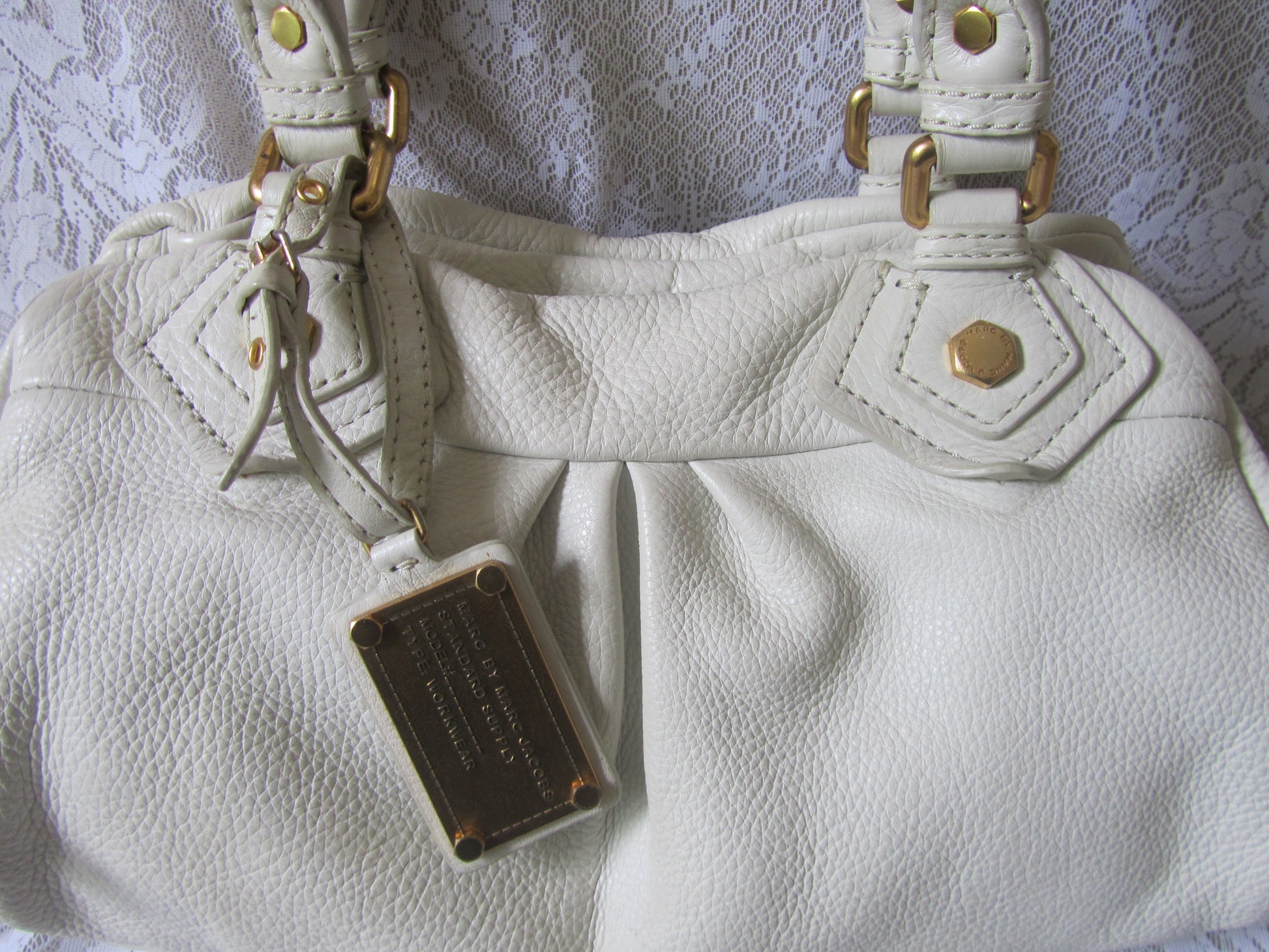 White leather handbag with gold accents on a white lace background
