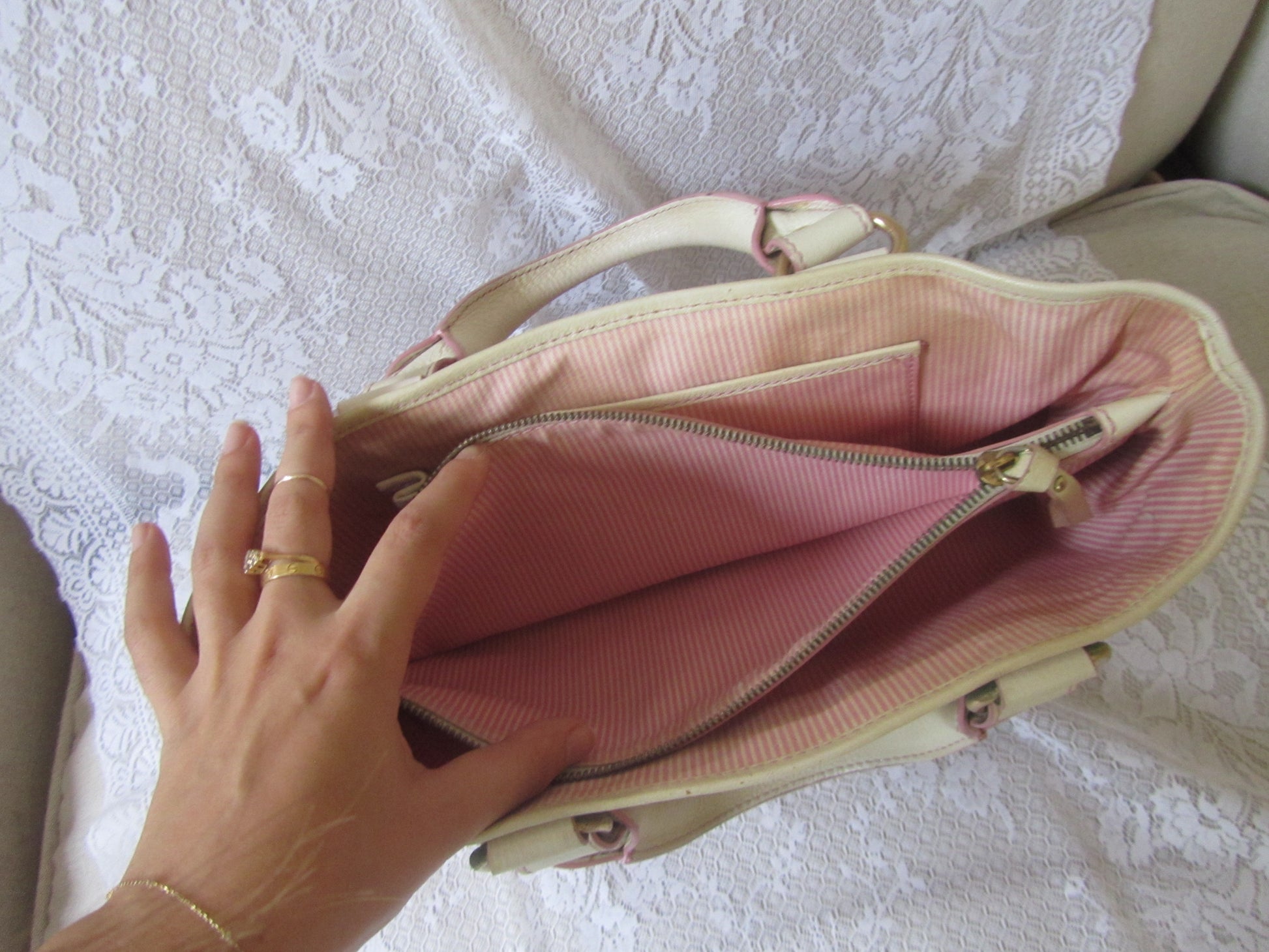 Pink handbag with a hand reaching inside on a textured white surface