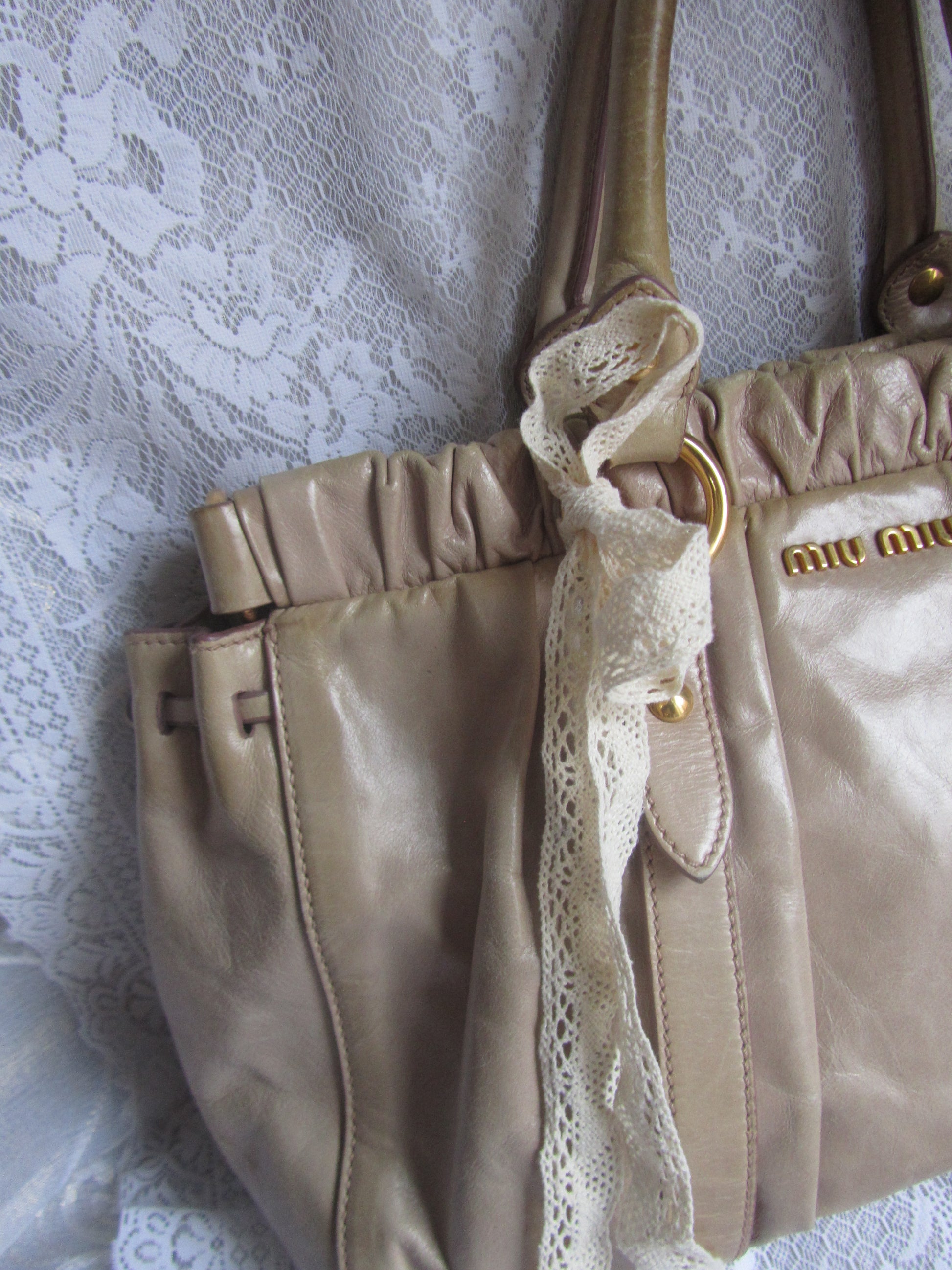 Close-up of beige leather handbag with lace trim on a textured surface