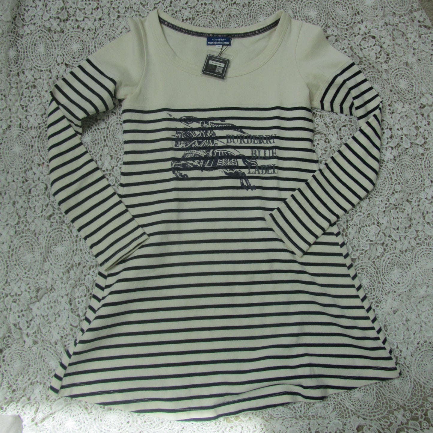 Striped long-sleeve shirt with a logo on a textured surface