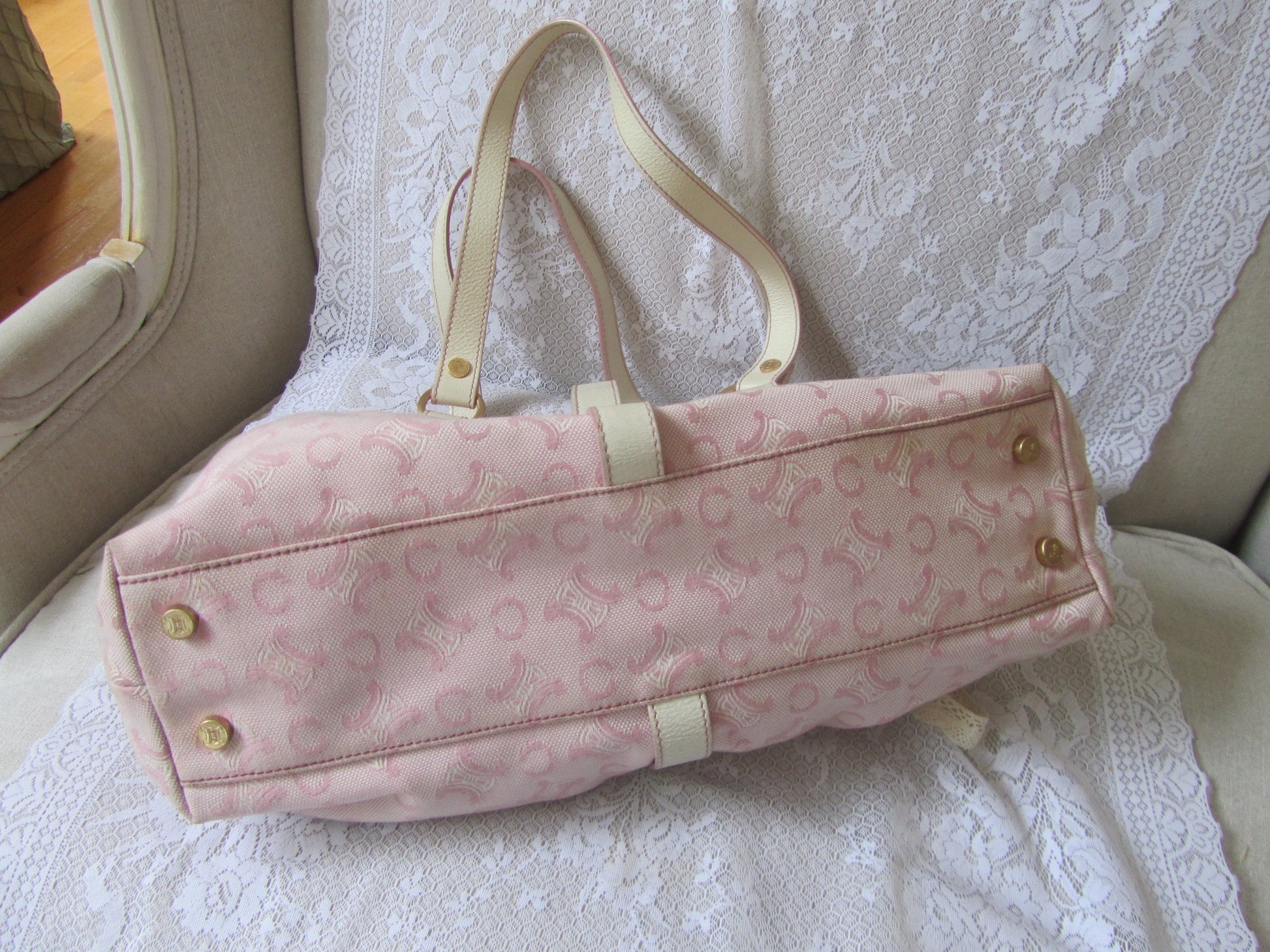 Pink handbag with gold buttons on a lace-covered surface