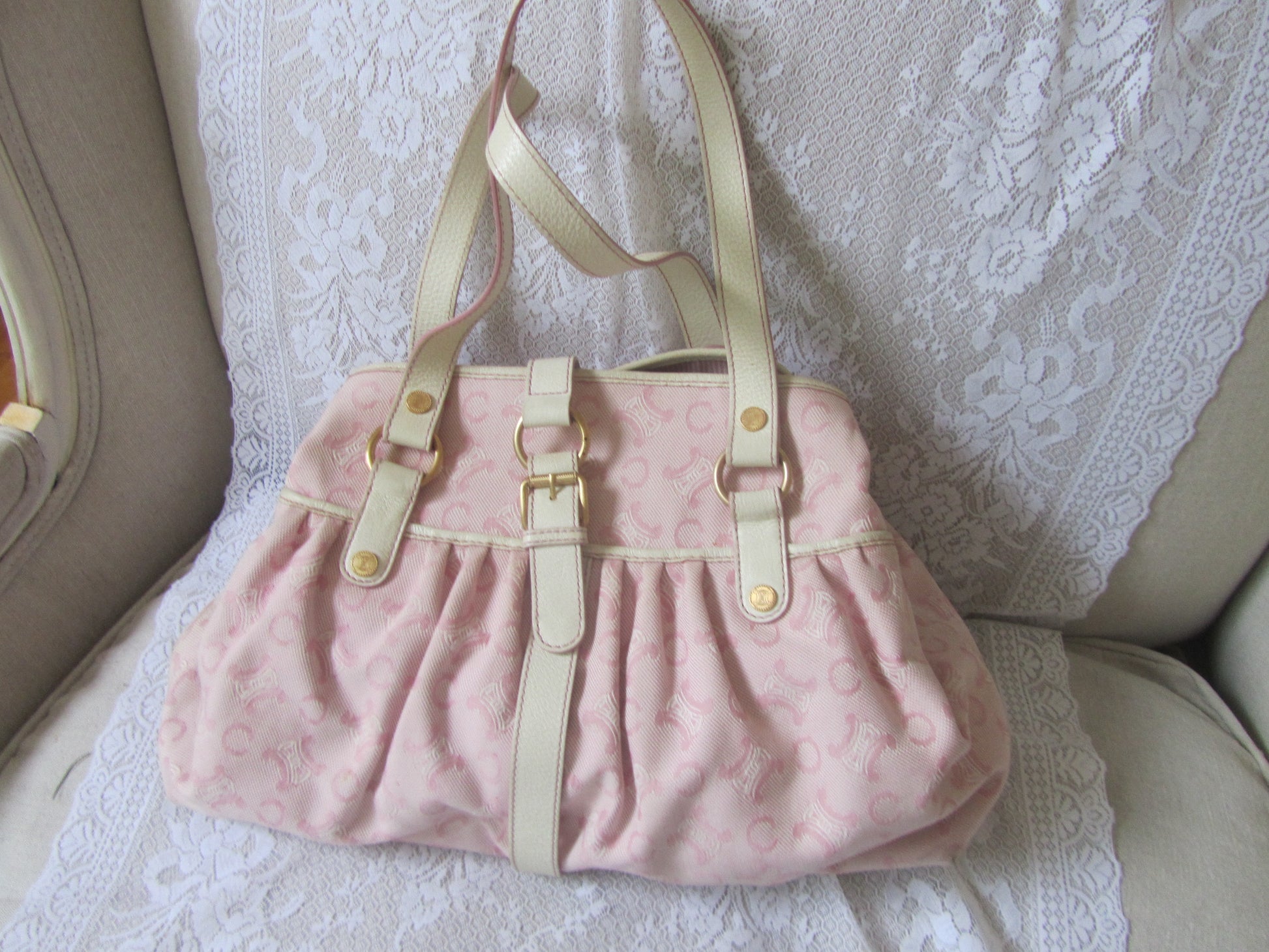 Pink handbag with beige straps on a textured white surface
