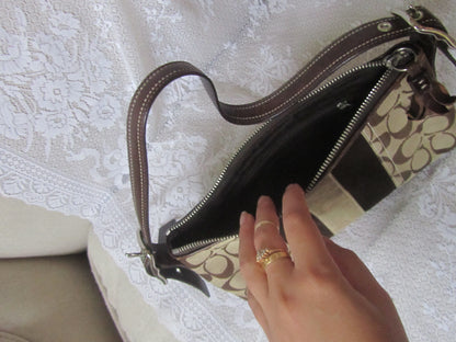 Hand holding a Coach handbag with a patterned background