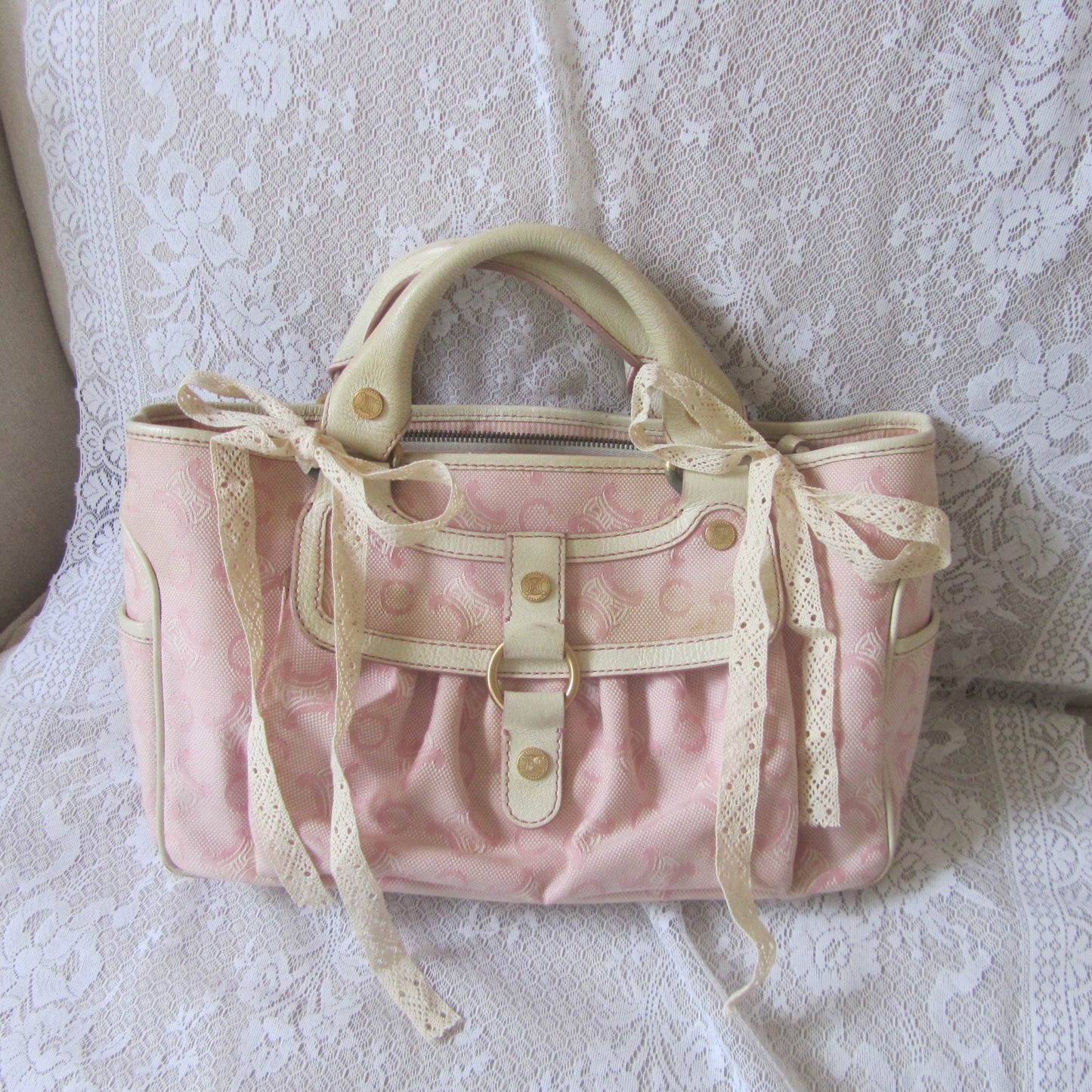 Pink handbag with lace details on a textured surface