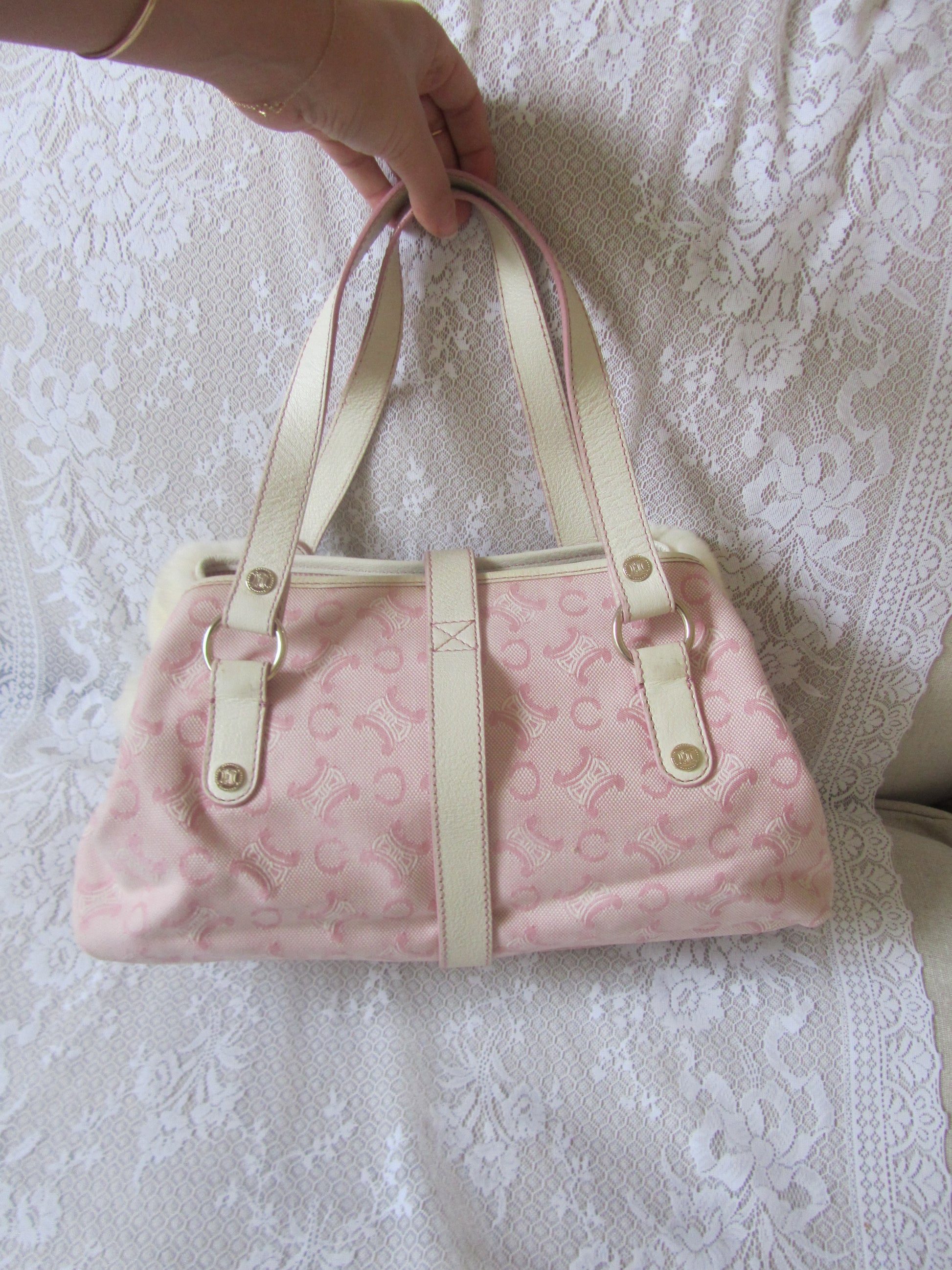 Pink bag with beige straps on a white lace background