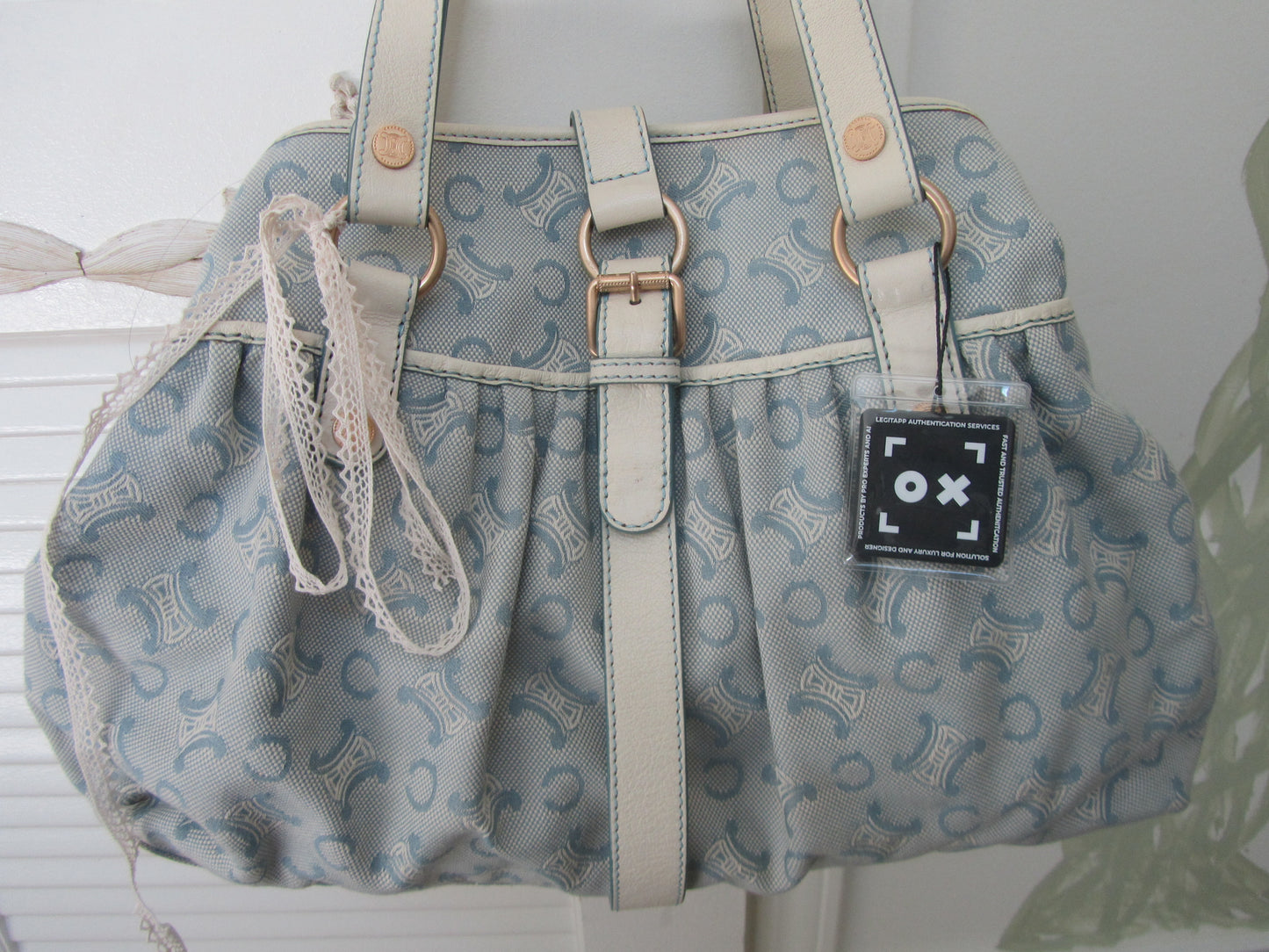 Gray patterned handbag with a visible brand tag on a white background