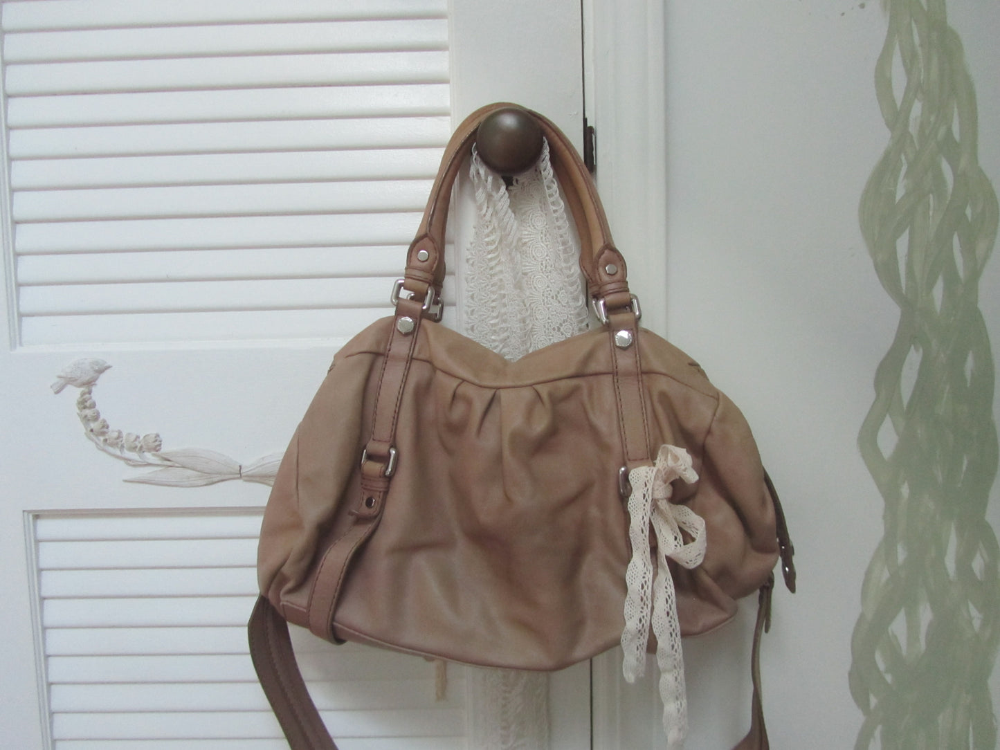 Brown handbag with decorative elements hanging on a door handle.