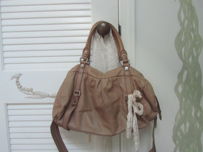 Brown handbag with decorative elements hanging on a door handle.