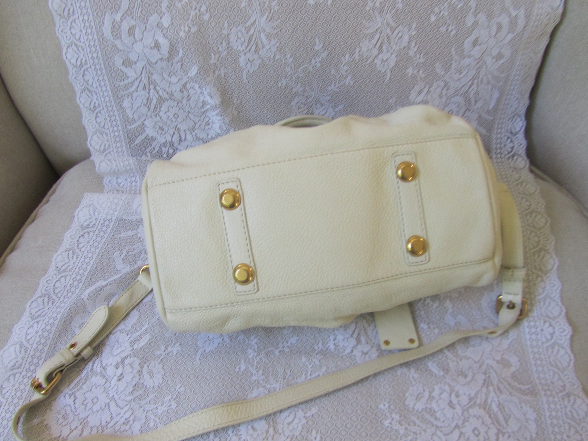 Beige handbag with gold accents on a textured white surface