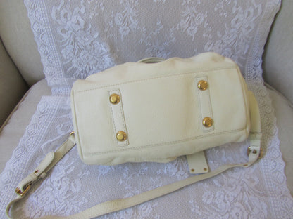 Beige handbag with gold accents on a textured white surface