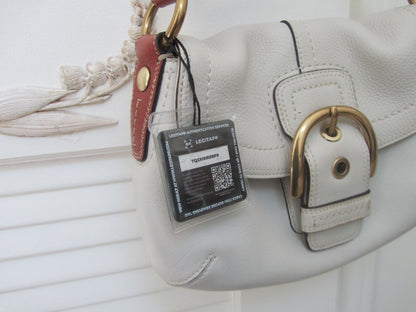 White handbag with a gold buckle and a visible authenticity tag on a white background