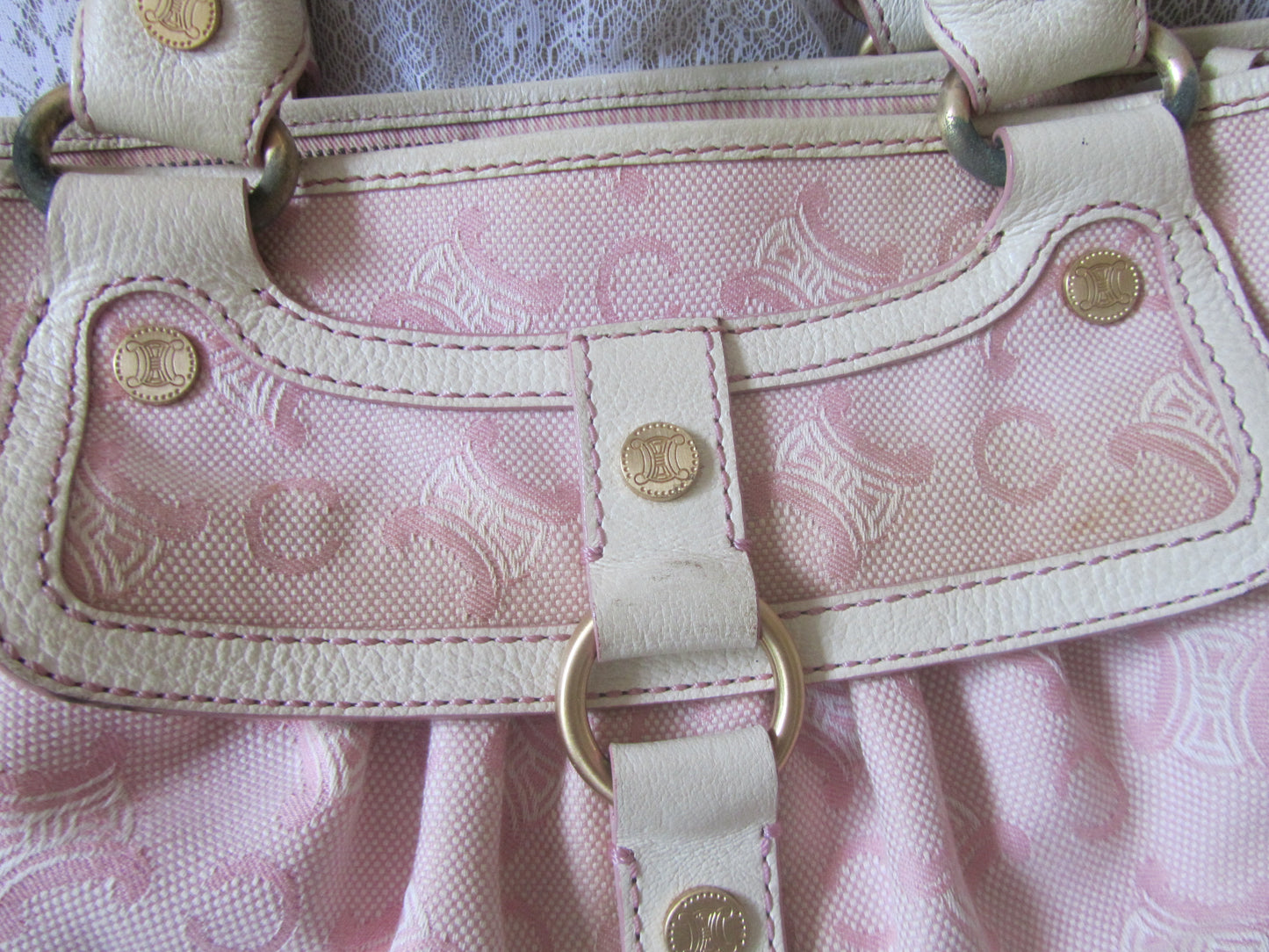 Pink handbag with gold accents on a matching pink fabric background