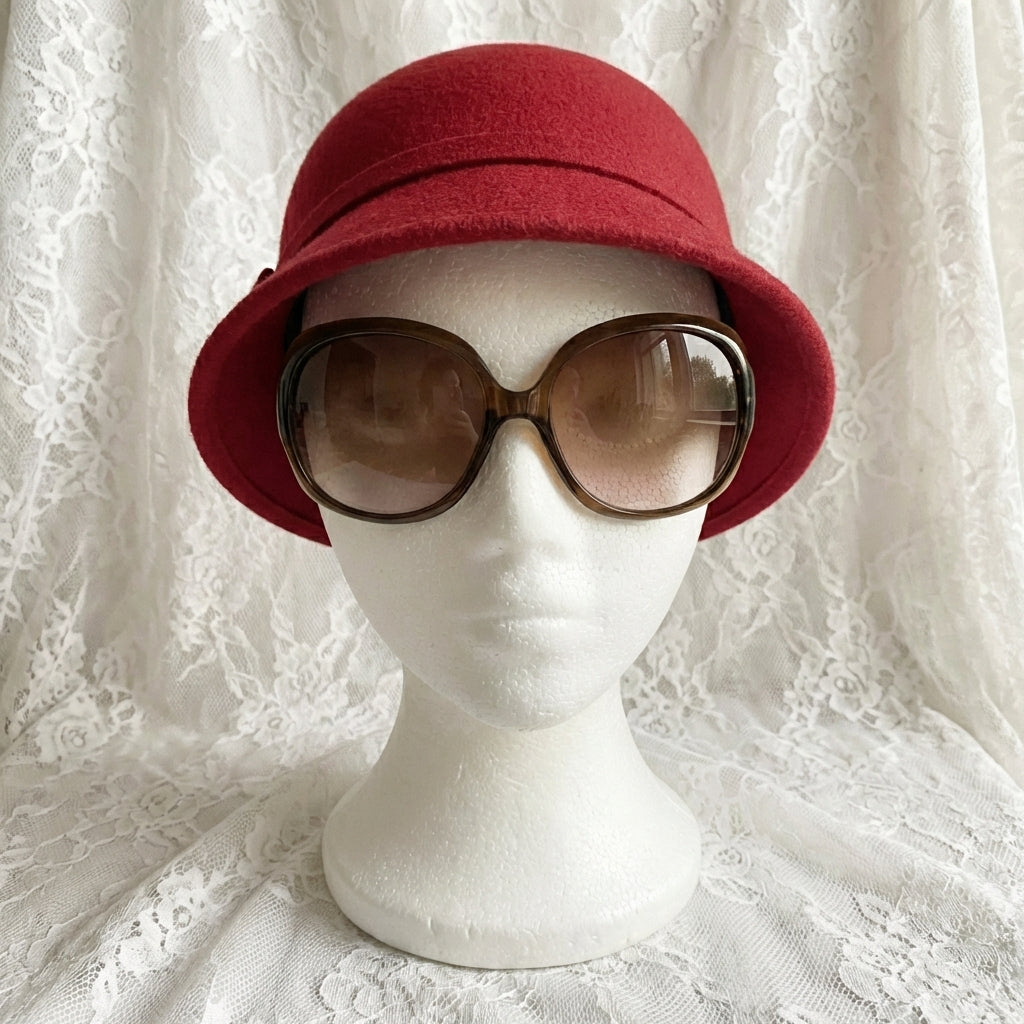 Red hat on a mannequin head with sunglasses, against a white lace background