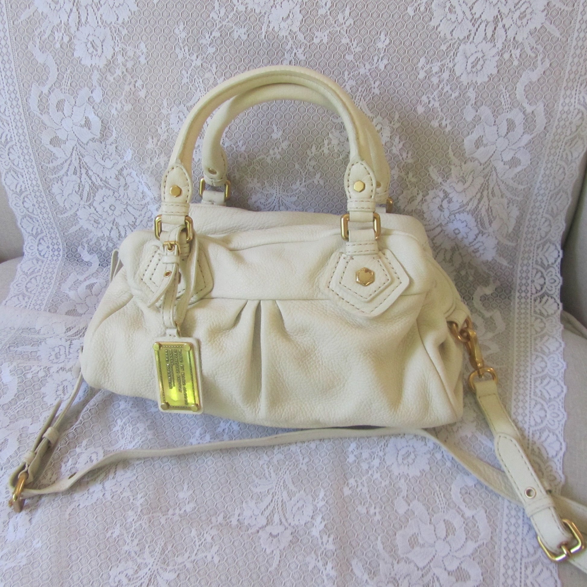 Beige handbag with gold accents on a white lace background