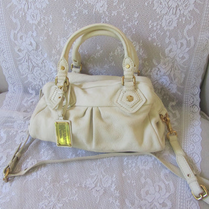 Beige handbag with gold accents on a white lace background