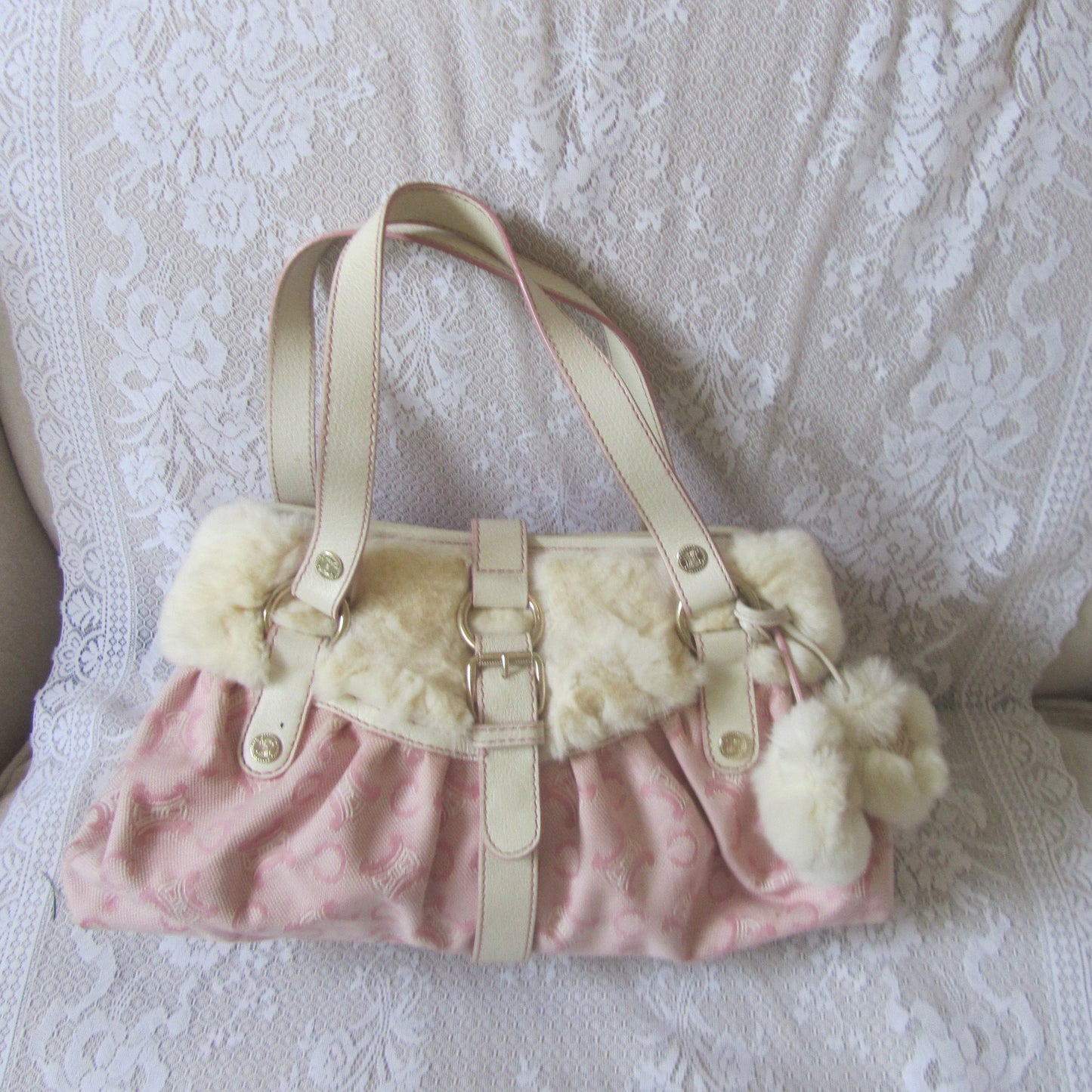 Pink handbag with white fur trim on a textured surface
